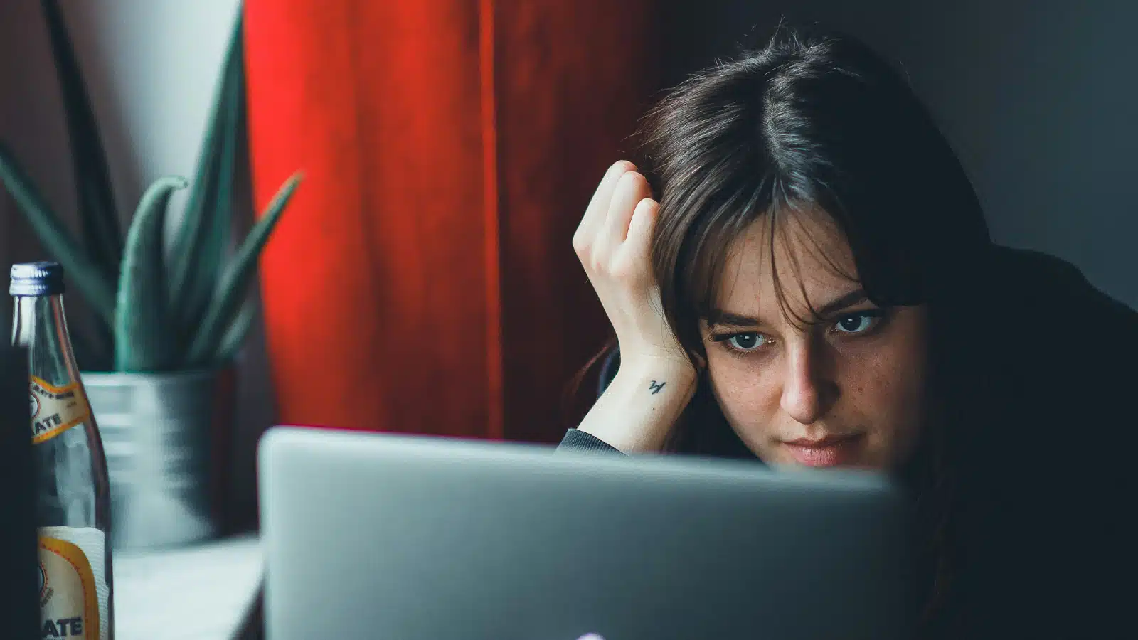 For the "too emotionally invested in work" article, a woman with long dark hair leaning her head on her hand and staring at a laptop screen